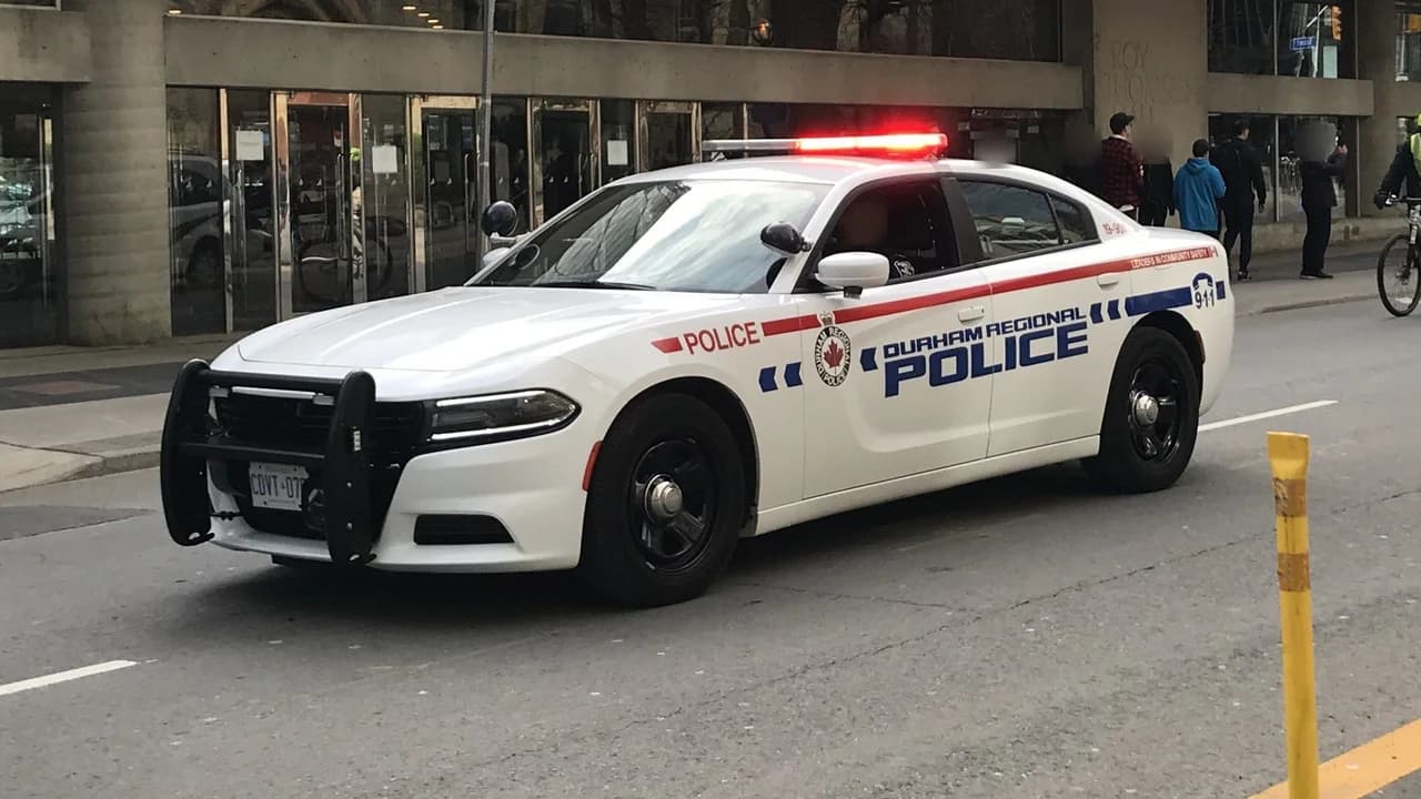 A Durham Regional Police cruiser with emergency lights on a city street.