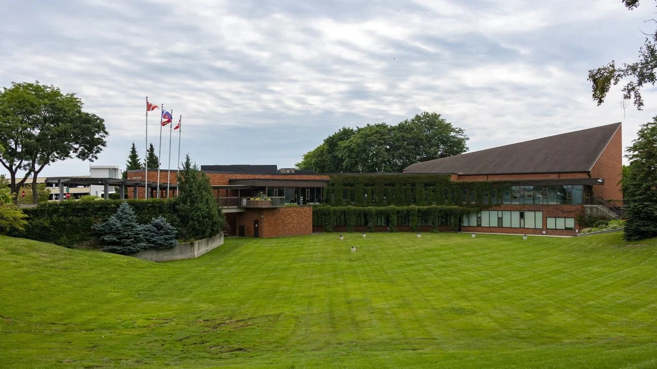 Whitby Town Hall on Rossland Road in Whitby, Ontario, a brick municipal building with flagpoles and a large lawn.