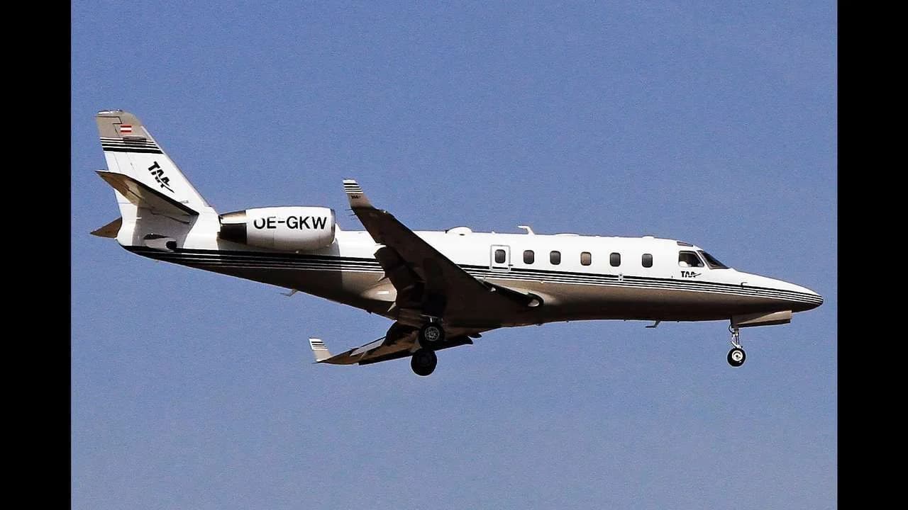 A white Gulfstream G100 air ambulance jet in flight against a clear blue sky; no people visible.